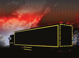 Camión negro con cinta reflectante amarilla destacada en carretera al atardecer