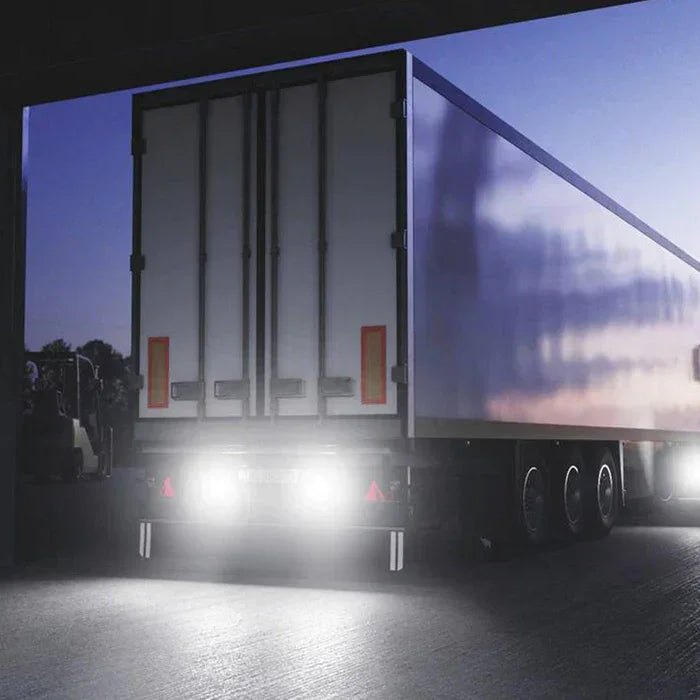 Camión con iluminación LED auxiliar encendida en zona de carga al atardecer