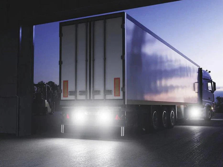 Camión de carga iluminado con focos LED auxiliares encendidos al anochecer en zona de almacenamiento