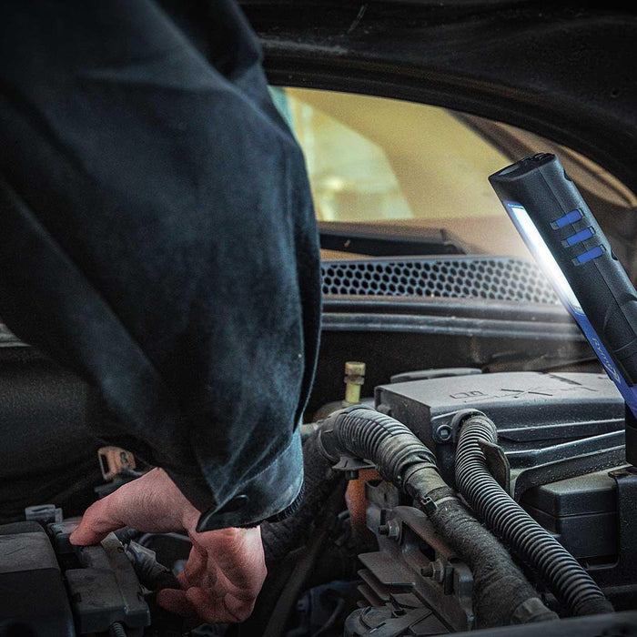 Lámpara LED RymeAutomotive Mini Max Pro iluminando el motor de un coche mientras una persona realiza mantenimiento